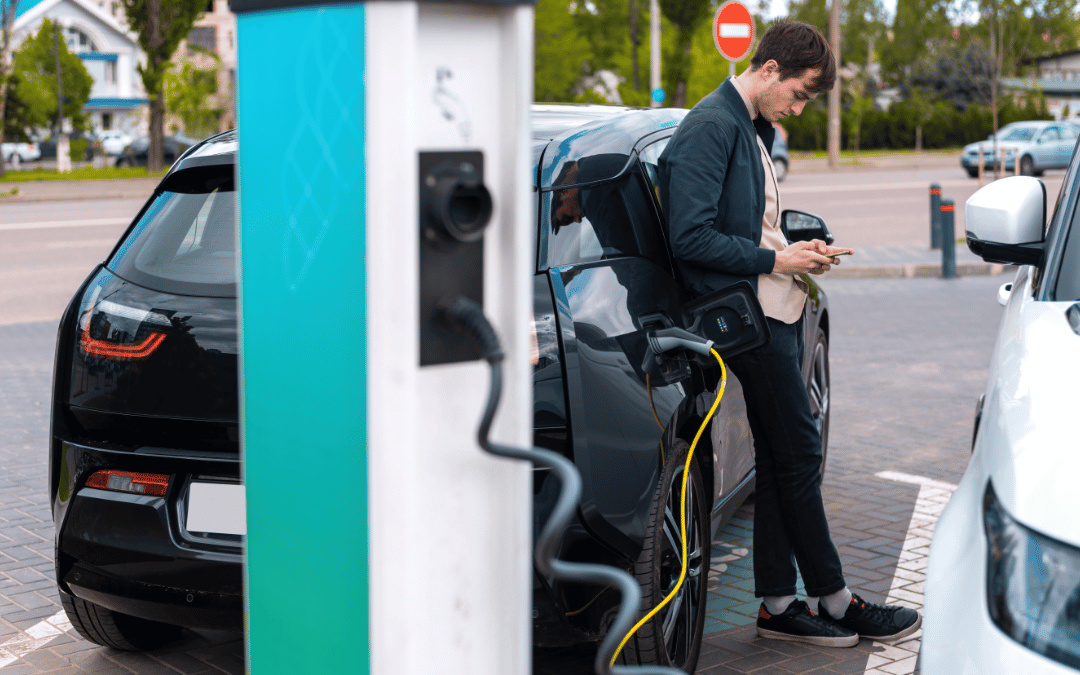 man charging electric car in orange county to see how many miles an electric car can go