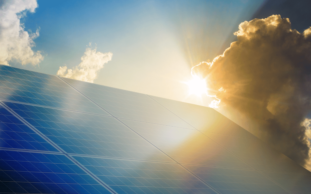 close-up of solar panels with the sun shining through clouds, highlighting the potential for energy security and sustainable power solutions for orange county businesses using solar energy.